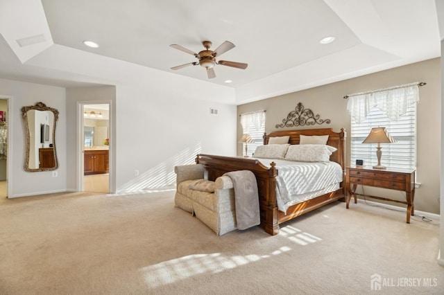 carpeted bedroom featuring ceiling fan, connected bathroom, and a tray ceiling