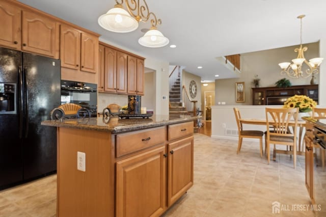 kitchen featuring a kitchen island, decorative light fixtures, dark stone counters, a chandelier, and black appliances