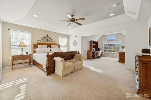 bedroom with ceiling fan, light colored carpet, and a tray ceiling