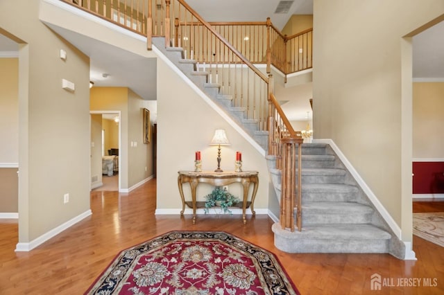 stairs featuring crown molding, a towering ceiling, and hardwood / wood-style floors