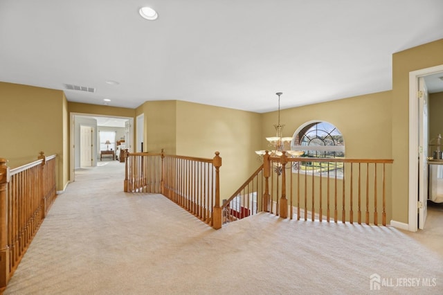 corridor featuring light carpet and an inviting chandelier