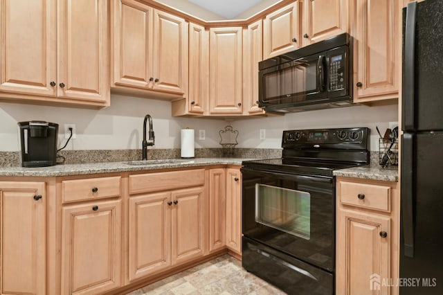 kitchen with black appliances, light brown cabinets, sink, and light stone counters