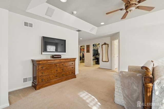 sitting room featuring ceiling fan, light colored carpet, and a tray ceiling