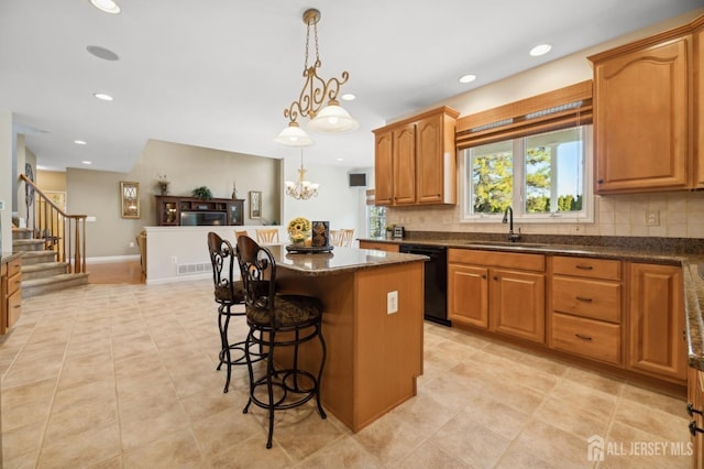 kitchen featuring dishwasher, hanging light fixtures, a kitchen island, a breakfast bar, and sink