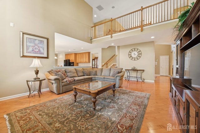 living room with a high ceiling and light wood-type flooring