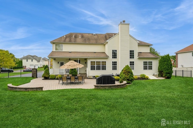 back of house featuring a lawn, ceiling fan, and a patio