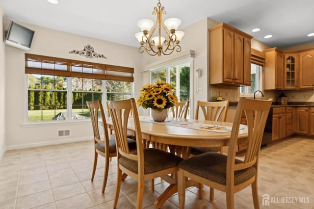 tiled dining space with sink and an inviting chandelier