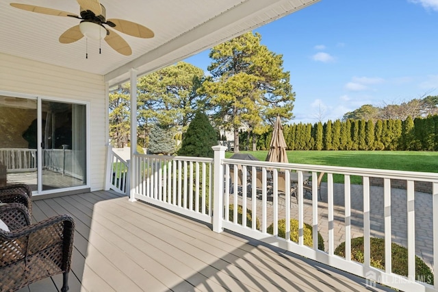 wooden terrace featuring ceiling fan and a lawn