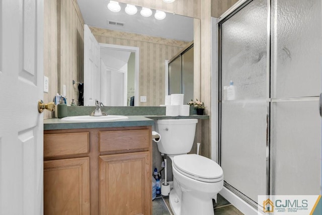 bathroom featuring vanity, toilet, a shower with door, and tile patterned floors