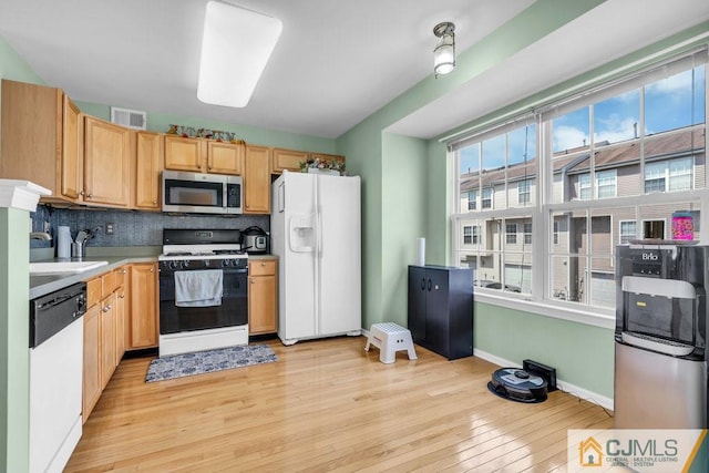 kitchen featuring white appliances, sink, light brown cabinets, light hardwood / wood-style floors, and decorative backsplash