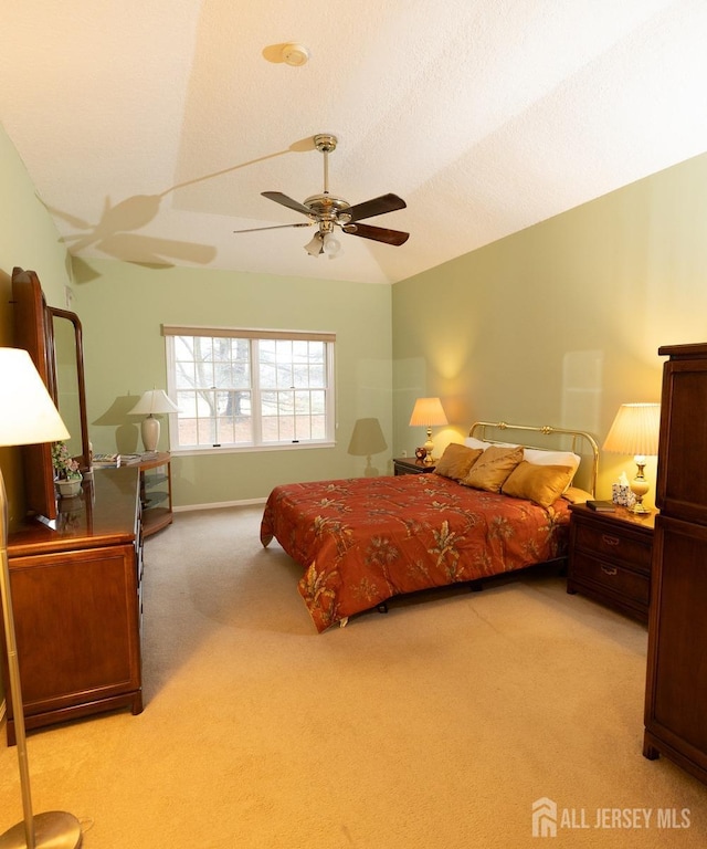 bedroom with a ceiling fan, lofted ceiling, light colored carpet, and a textured ceiling