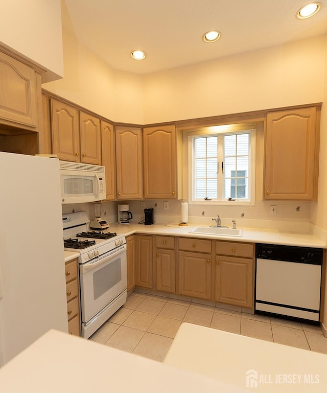 kitchen with white appliances, light countertops, a sink, and light brown cabinetry