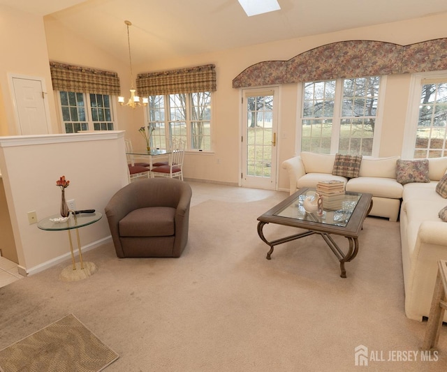 carpeted living room with lofted ceiling with skylight, baseboards, and a notable chandelier