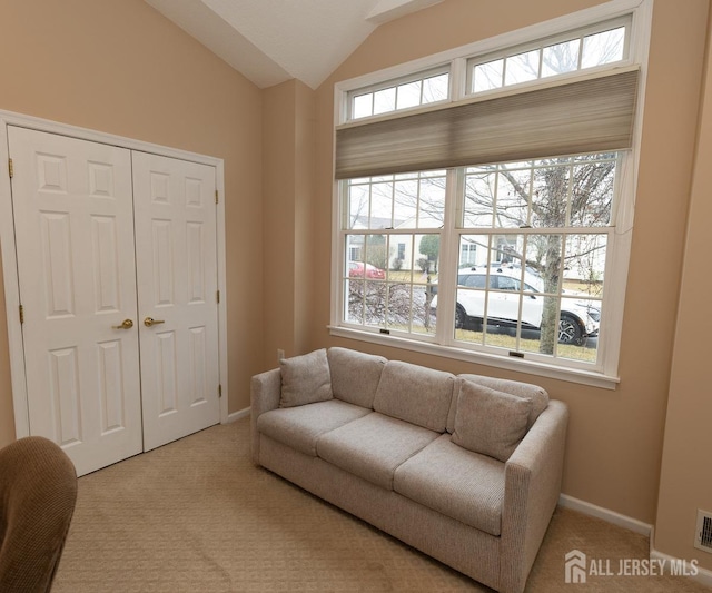 living area featuring light carpet, vaulted ceiling, visible vents, and baseboards