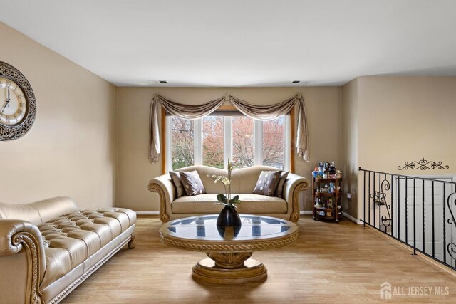 living room featuring visible vents, baseboards, and light wood finished floors