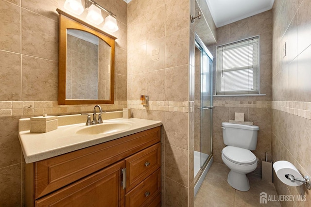bathroom with vanity, tile patterned floors, toilet, a shower stall, and tile walls