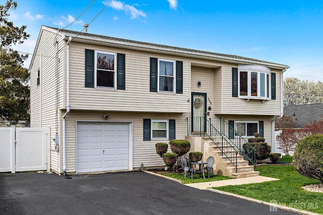 split foyer home with a garage, aphalt driveway, and fence