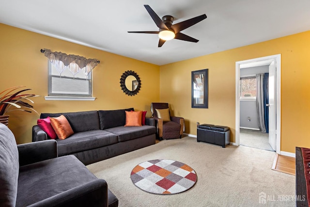 carpeted living area featuring ceiling fan and baseboards
