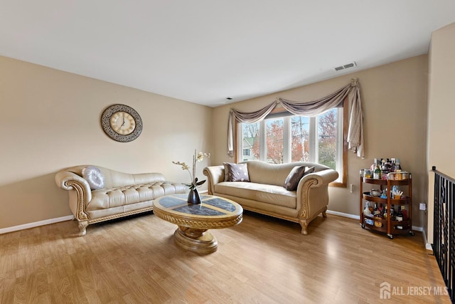 living room featuring visible vents, baseboards, and wood finished floors