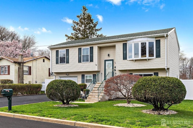 split foyer home with a garage, fence, driveway, and a front lawn