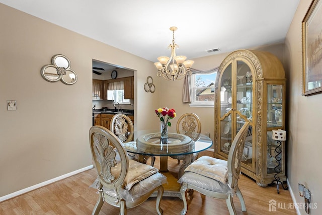 dining space with light wood finished floors, an inviting chandelier, baseboards, and visible vents