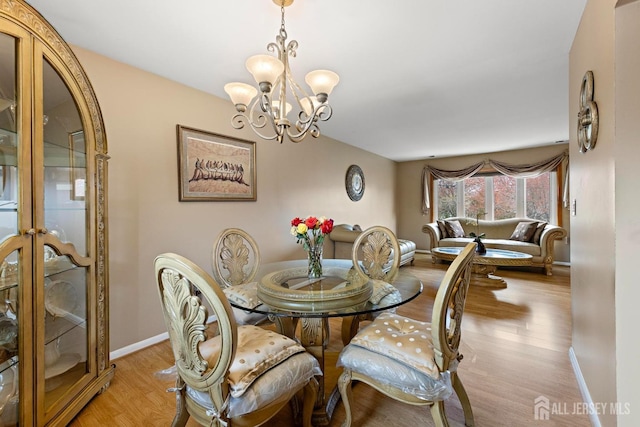 dining area with light wood-style flooring, baseboards, and an inviting chandelier