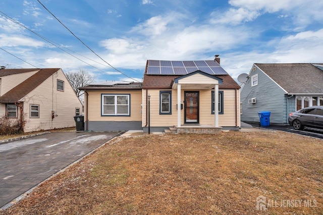 bungalow-style house with a front yard and solar panels