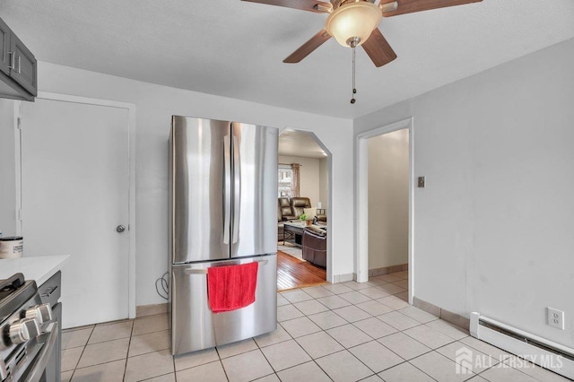 kitchen with a baseboard heating unit, light tile patterned floors, stainless steel appliances, and ceiling fan