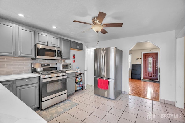 kitchen featuring tasteful backsplash, stainless steel appliances, gray cabinets, and light tile patterned floors