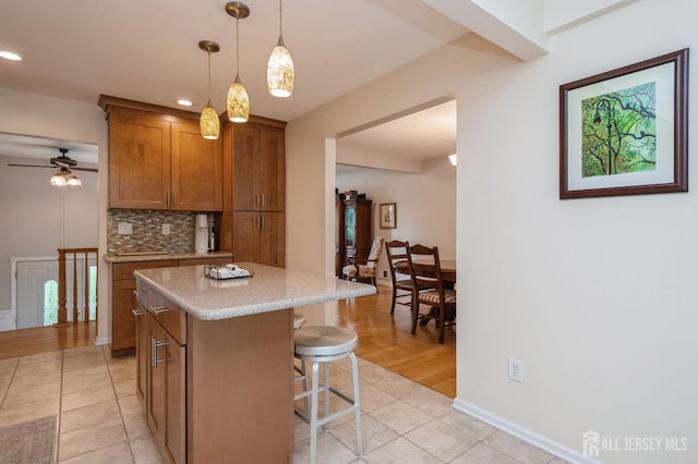 34 Bartman Rd, East Brunswick, NJ 08816 - kitchen featuring light tile patterned floors, brown cabinets, decorative backsplash, a breakfast bar area, and a center island