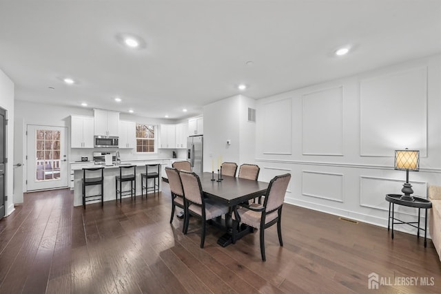 dining room with a decorative wall, recessed lighting, dark wood-style floors, and visible vents