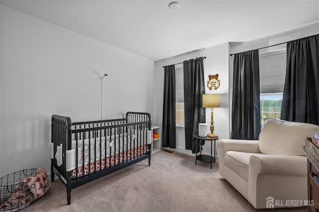 carpeted bedroom with a crib and baseboards