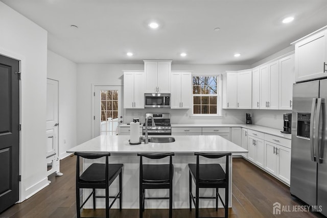 kitchen featuring a sink, dark wood-style floors, white cabinetry, stainless steel appliances, and light countertops