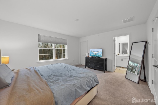 carpeted bedroom featuring a sink, visible vents, baseboards, and ensuite bath