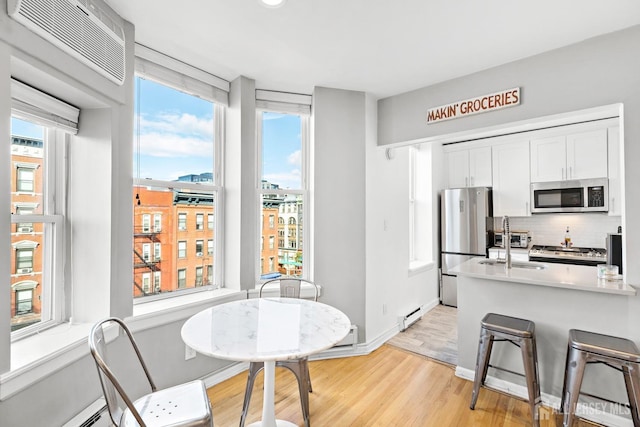 kitchen with stainless steel appliances, a baseboard heating unit, plenty of natural light, and tasteful backsplash