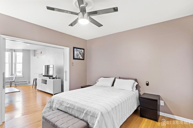 bedroom with ceiling fan, a baseboard radiator, light wood-style flooring, and baseboards