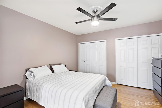 bedroom featuring ceiling fan, light wood finished floors, and two closets