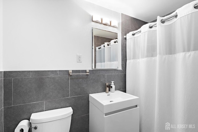 full bathroom with curtained shower, vanity, toilet, and tile walls