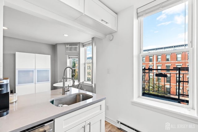 kitchen featuring white cabinets, dishwasher, light countertops, and a sink