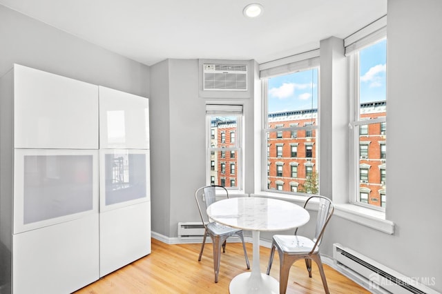 dining room featuring plenty of natural light, a baseboard radiator, and light wood-style floors