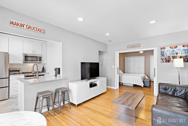 living room featuring light wood-style floors, recessed lighting, and a toaster