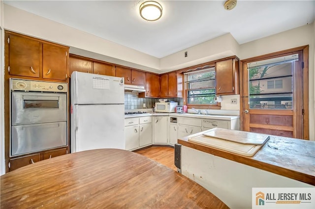 20 Kennedy St, Iselin, NJ 08830 - kitchen with white appliances, under cabinet range hood, light countertops, light wood-type flooring, and tasteful backsplash