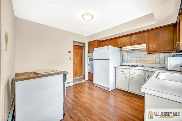 20 Kennedy St, Iselin, NJ 08830 - kitchen with white appliances, light countertops, under cabinet range hood, light wood-style floors, and backsplash