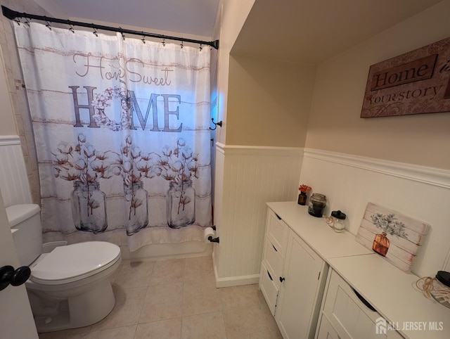 full bath featuring wainscoting, toilet, shower / tub combo with curtain, tile patterned flooring, and vanity