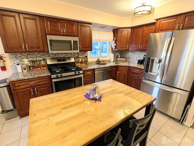 kitchen featuring decorative backsplash, stainless steel appliances, a sink, and light tile patterned flooring