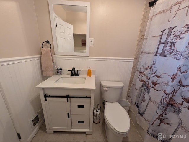 bathroom featuring visible vents, a wainscoted wall, vanity, and toilet