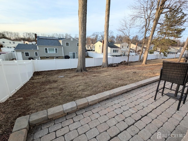 view of yard featuring a patio area, a fenced backyard, and a residential view