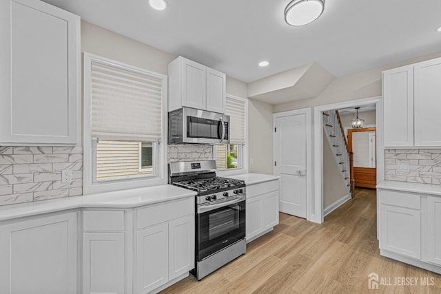 307 Wayne St, Highland Park, NJ 08904 - kitchen with appliances with stainless steel finishes, decorative backsplash, white cabinetry, light countertops, and light wood-style floors