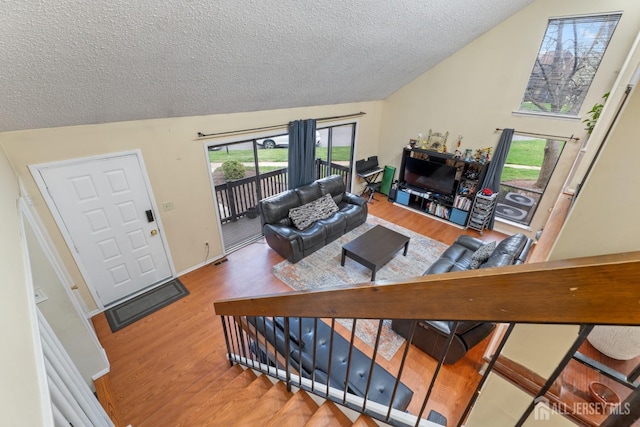 living room featuring visible vents, vaulted ceiling, wood finished floors, and a textured ceiling
