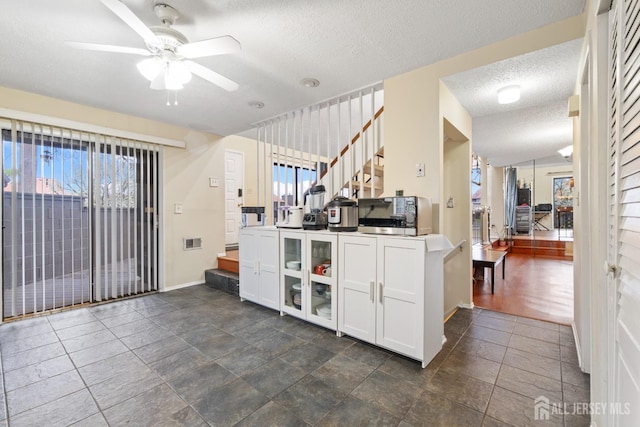 kitchen with ceiling fan, white cabinetry, a wealth of natural light, and a textured ceiling